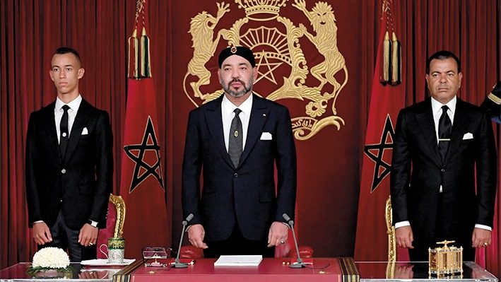 This handout picture released by the Moroccan Royal Palace shows Morocco's King Mohammed VI (C) delivering a speech to mark the 19th anniversary of his accession to the throne, beside his brother Prince Moulay Rachid (R) and son Hassan III, in Al Hoceima on July 29, 2018. / AFP PHOTO / Moroccan Royal Palace / Handout / RESTRICTED TO EDITORIAL USE - MANDATORY CREDIT "AFP PHOTO / MOROCCAN ROYAL PALACE" - NO MARKETING NO ADVERTISING CAMPAIGNS - DISTRIBUTED AS A SERVICE TO CLIENTS